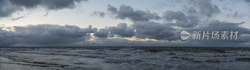 日落时波罗的海戏剧性的多云天空，船只在地平线上。