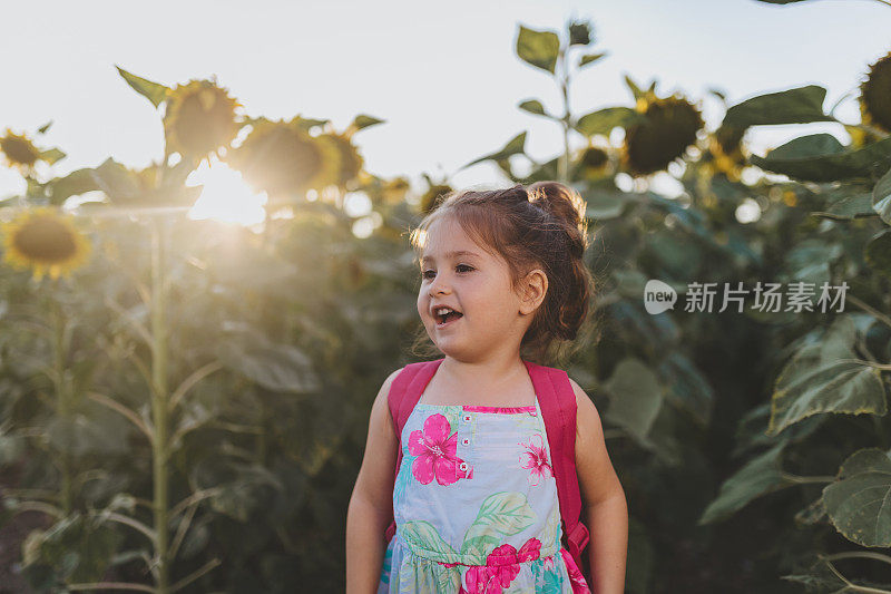 在向日葵地里微笑的蹒跚学步的小女孩