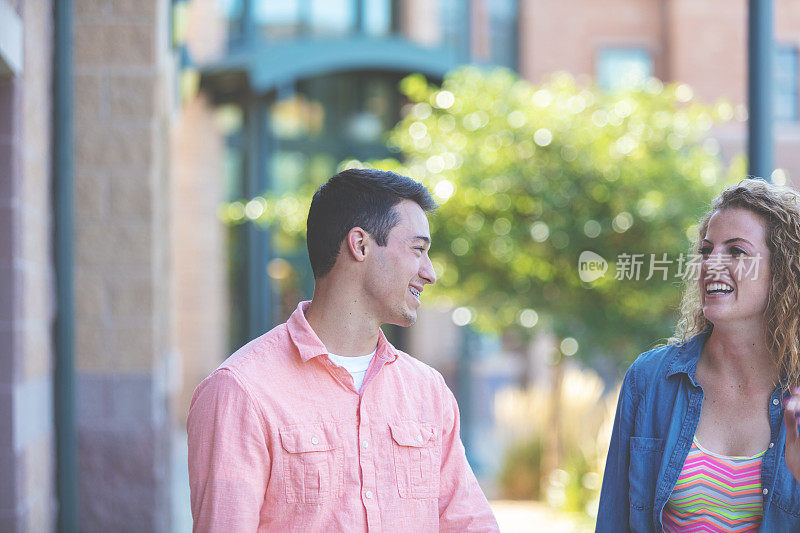 男和女年轻的大学年龄的朋友在一个大学公共区域的户外进行有趣的谈话