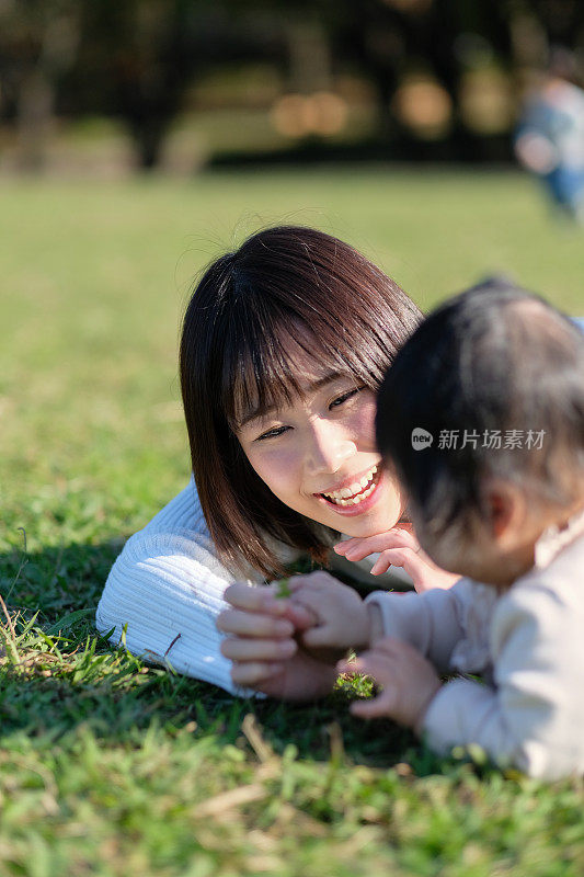 妈妈在公园的草地上和婴儿说话