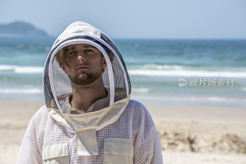 一个穿着蜜蜂防护服的年轻人在拜伦湾附近的海滩上。