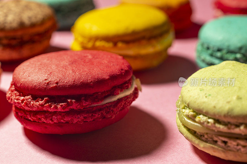 近距离拍摄色彩鲜艳的自制蛋白杏仁饼干，背景是粉红色。