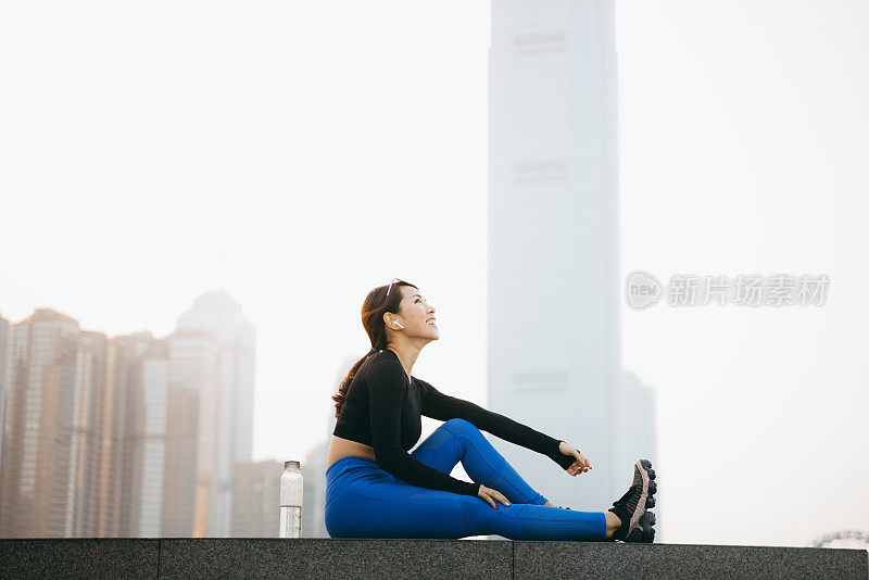 自信年轻的运动妇女休息和饮水，而户外锻炼在城市