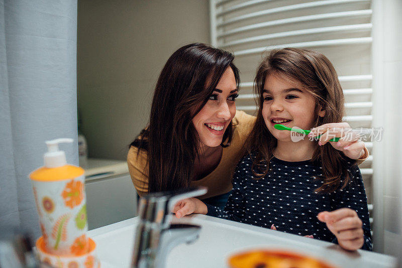 一个正在刷牙的女人和一个小女孩