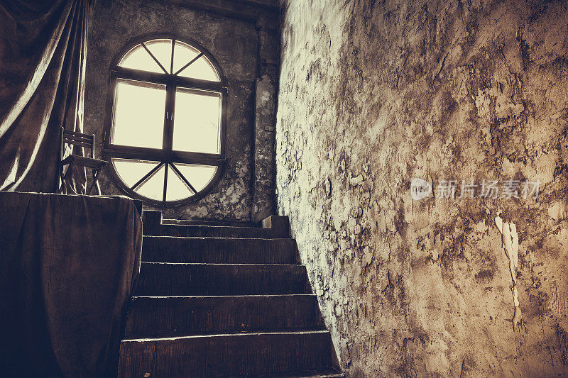一间古老的房间，有一扇圆窗和一段石头楼梯
