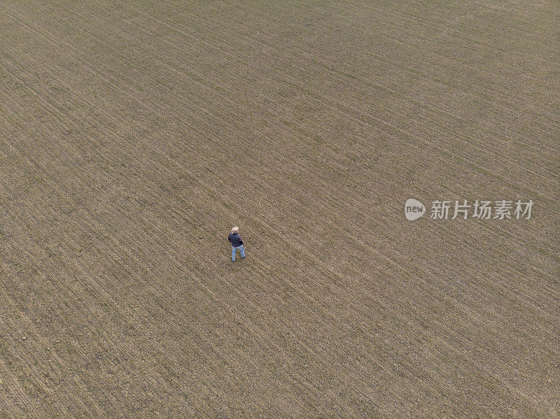 冬末英俊的成年农民在他的麦苗农地里。鸟瞰图。