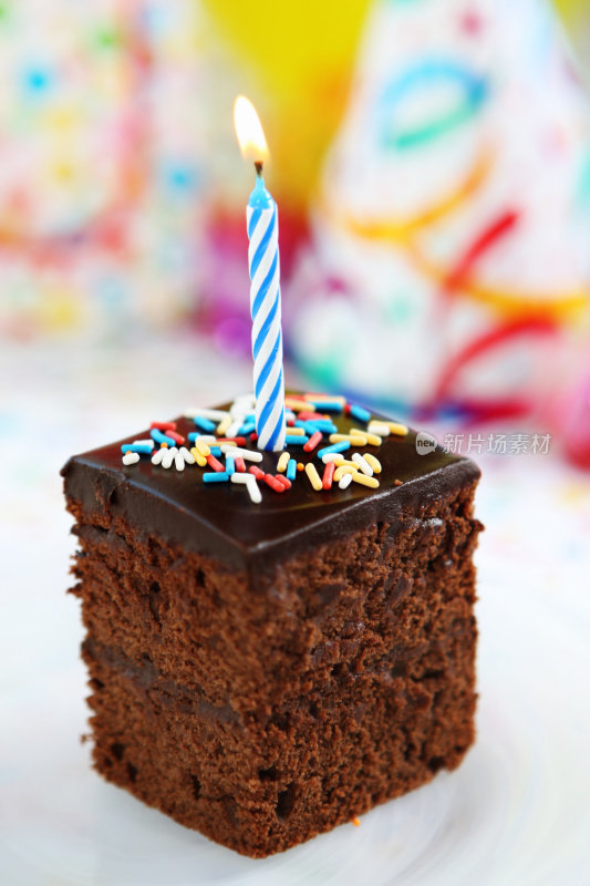 一片巧克力蛋糕和一支点燃的生日蜡烛