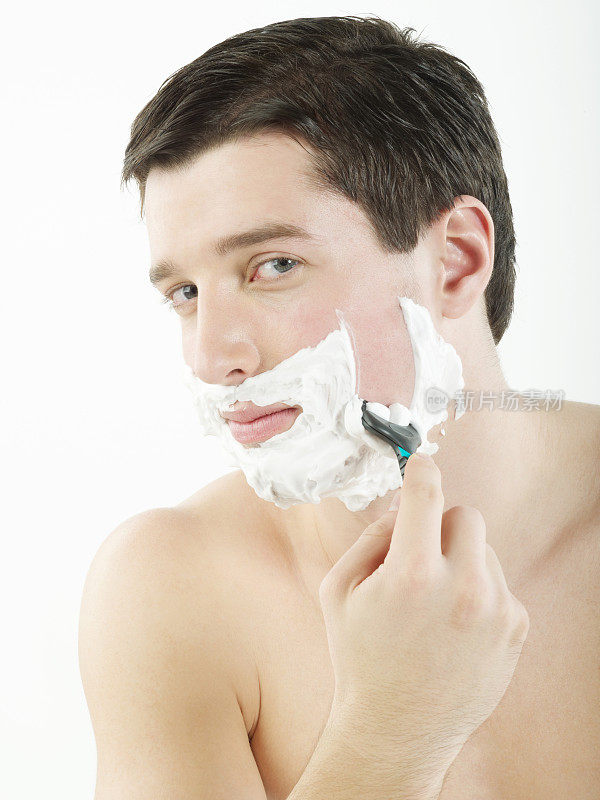 英俊的男人用剃须刀刮胡子
