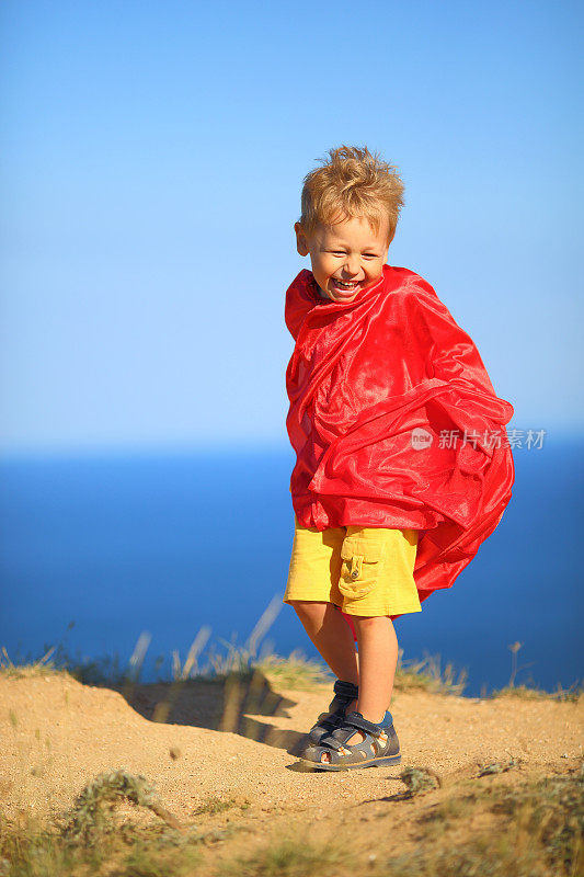 海岸上有趣的超级英雄男孩