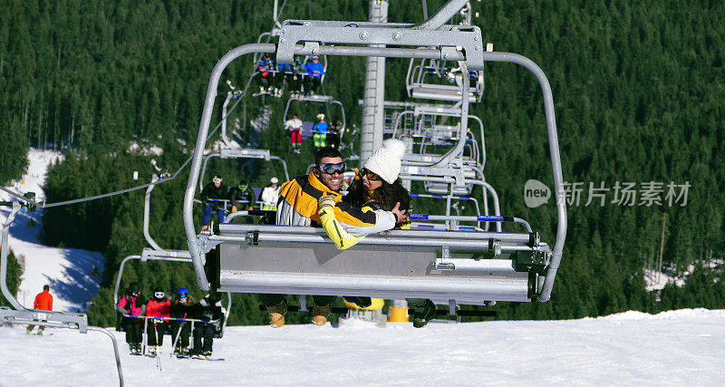 一对兴高采烈的年轻夫妇正乘滑雪缆车下山