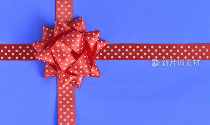 一个蓝色包装的礼物，上面有一个红色的大蝴蝶结