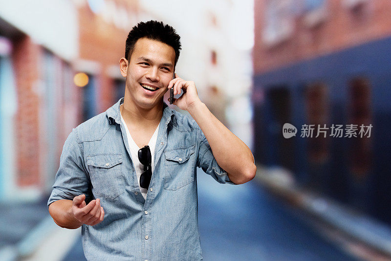 微笑的男人在城市前面讲手机
