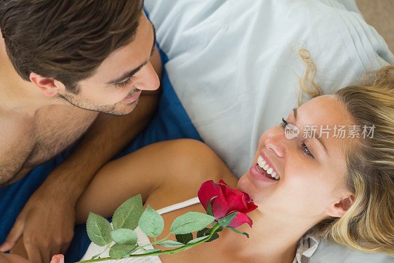 快乐男友捧着红玫瑰抚摸女友的下巴