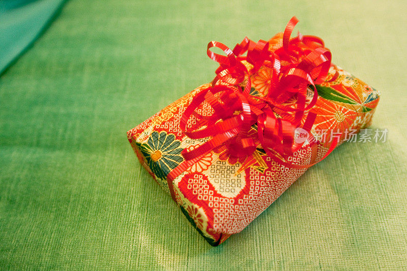 愉快明亮的橙色和红色包装的礼物在绿色的背景