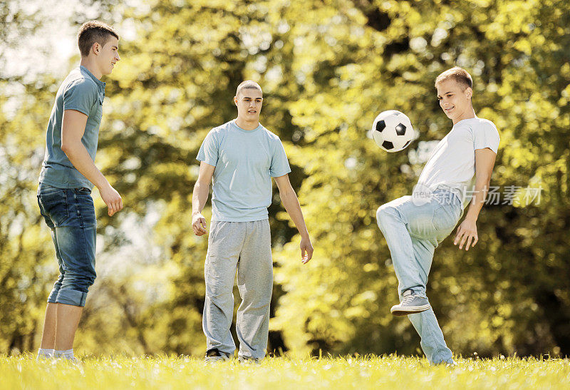 十几岁的男孩在公园里踢足球。