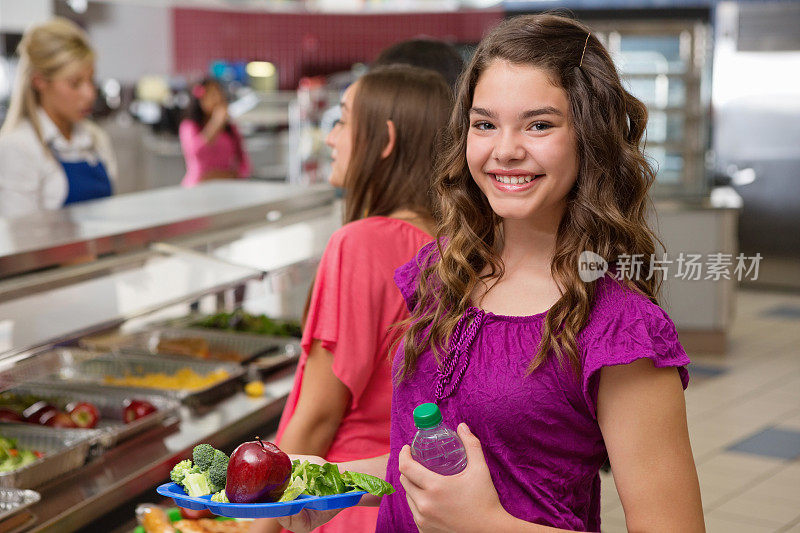 快乐的中学女生在自助餐厅排队买健康午餐