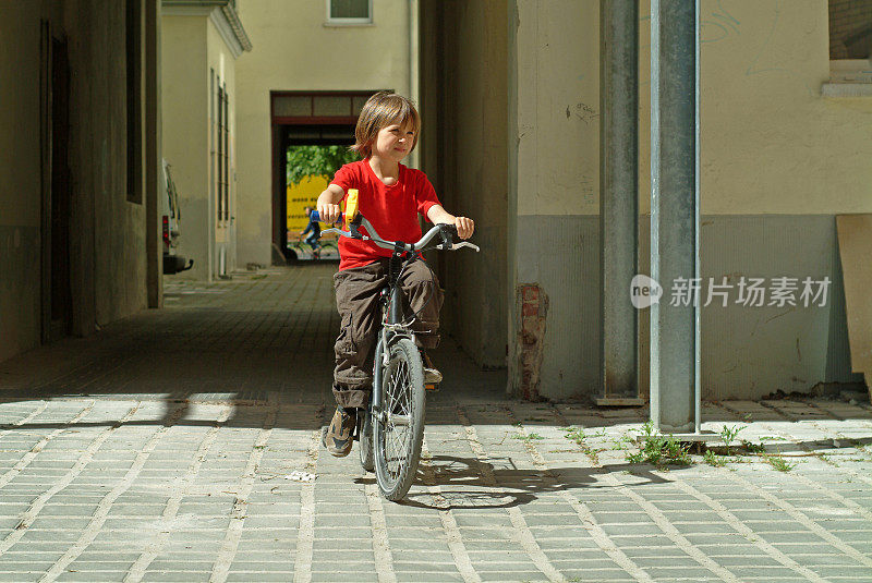 小男孩在城市的院子里骑车