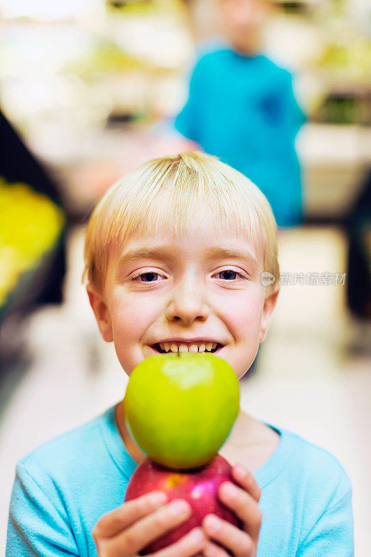 可爱，微笑的金发小女孩在超市挑选苹果