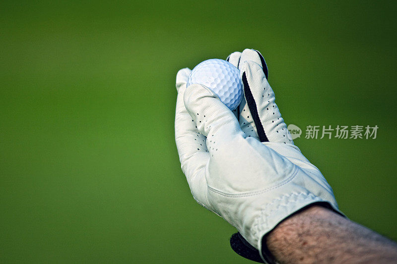 用手套握着高尔夫球