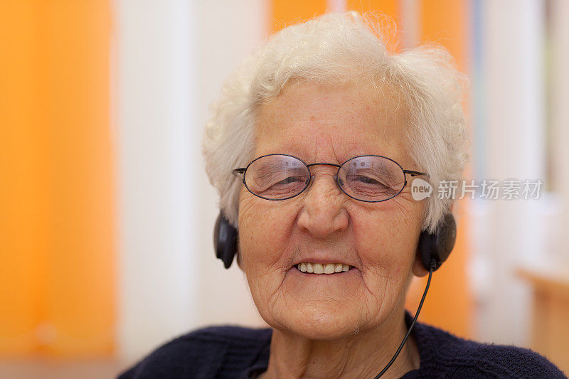 肖像快乐的老妇人戴着耳机