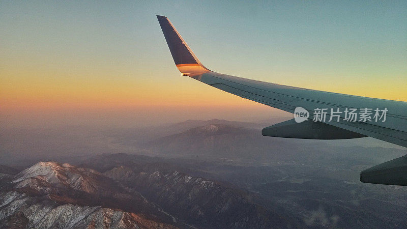空中日落飞行，积雪覆盖的加利福尼亚山脉，飞机机翼