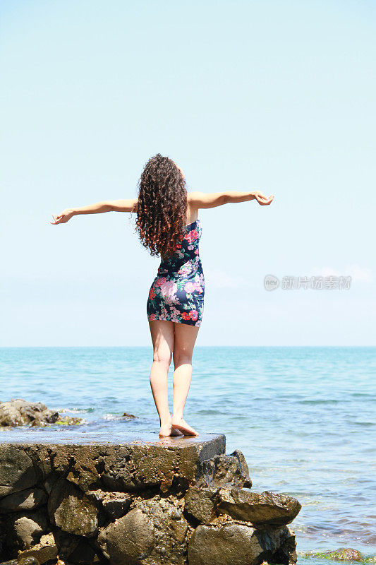 美丽的年轻女子感觉自由在风中靠近海滩