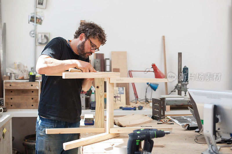 一个家具工匠在他的工作室里雕刻一把椅子