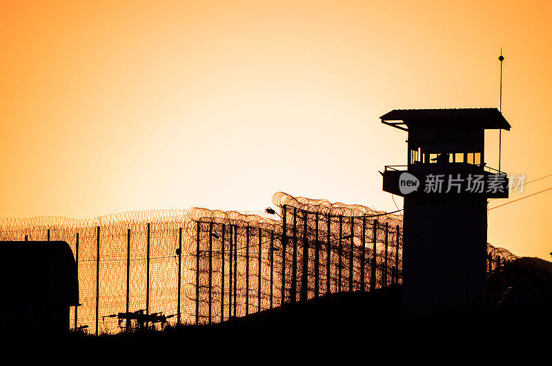 监狱的铁丝网和瞭望塔的剪影。