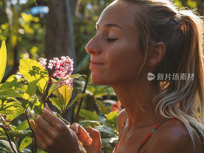 年轻女子照顾植物在异国情调的花园