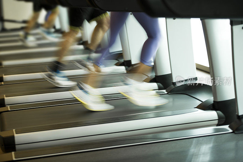 男性和女性在健身房的跑步机上跑步