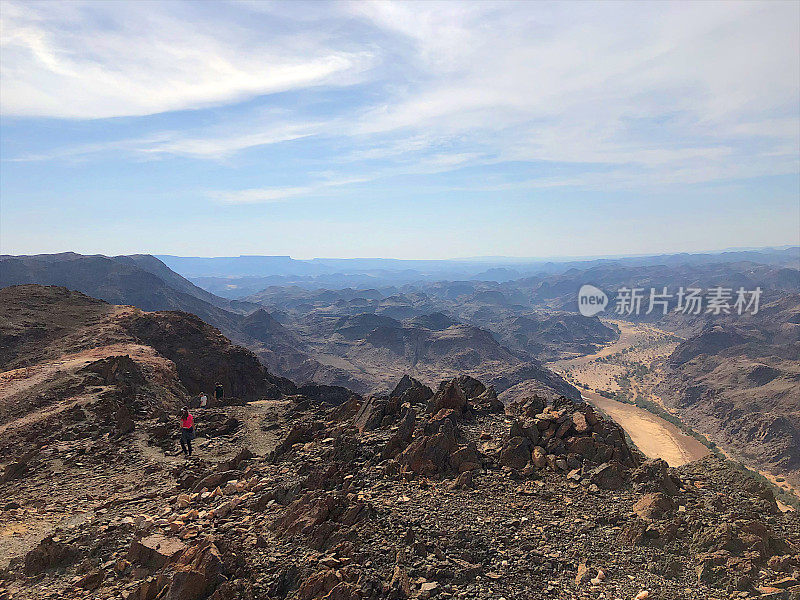 一群孩子徒步旅行贫瘠的山区景观与河流峡谷下面