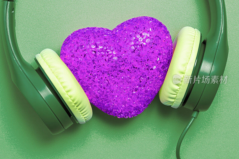 爱的音乐(绿色背景下紫色心形的耳机)