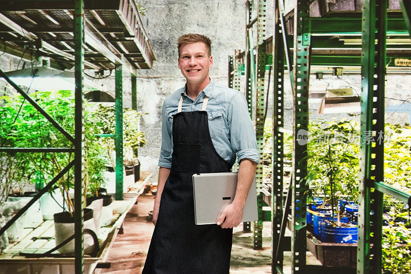 大麻店-一名男性员工正拿着一台笔记本电脑