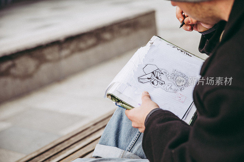年轻的涂鸦艺术家在城市街道上素描