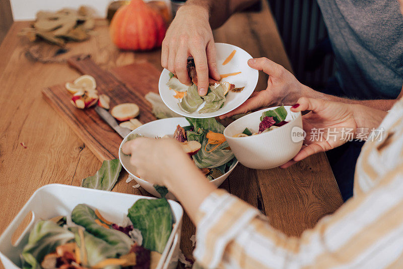 特写的男人和女人堆肥的食物剩饭