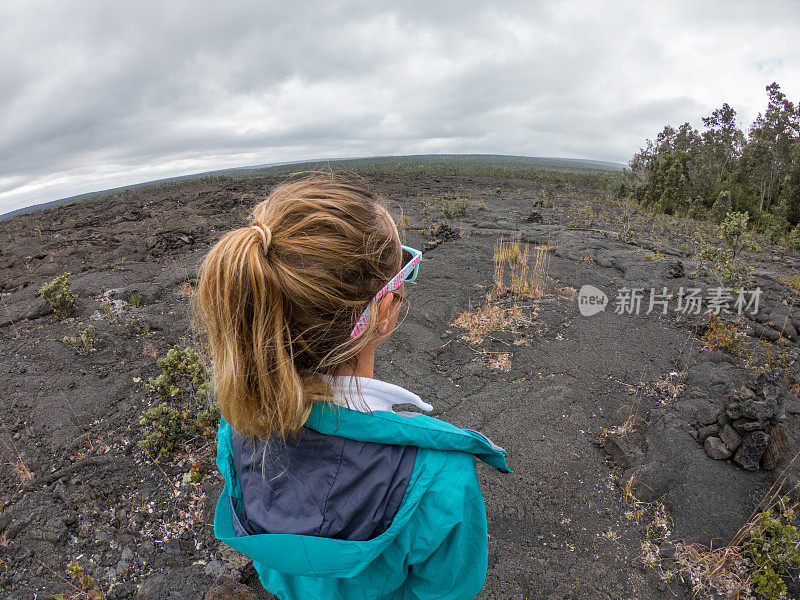 一名年轻女子站在夏威夷火山国家公园的熔岩上