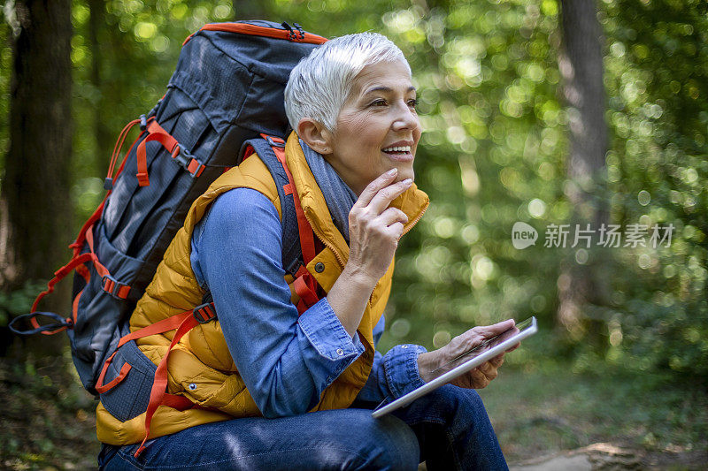 老年妇女在春天的森林徒步旅行。