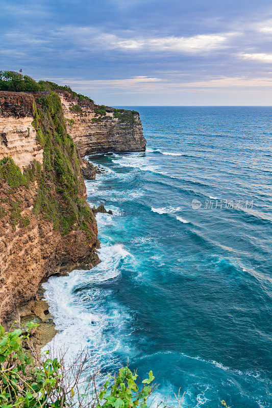 Uluwatu巴厘岛。蓝色的海洋和岩石山，覆盖着热带树木。