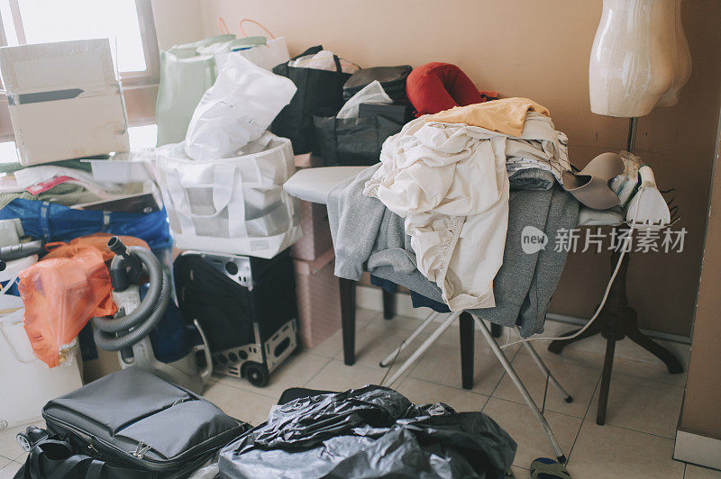 不整洁的家庭房间，熨衣板上满是展开的脏衣服