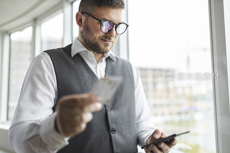 拿着信用卡用手机的男人