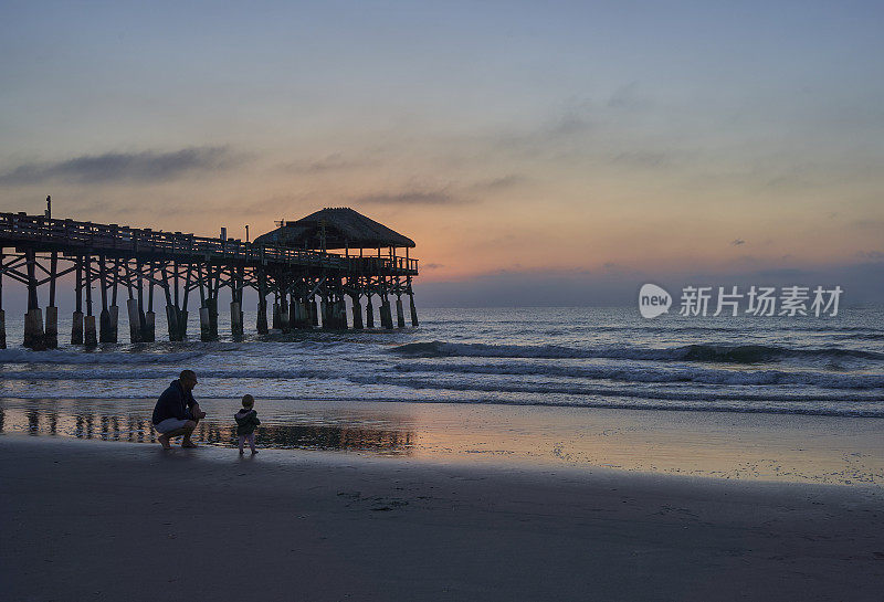 父亲和女儿享受海滩和充满活力的日出在可可海滩码头，佛罗里达中部美国
