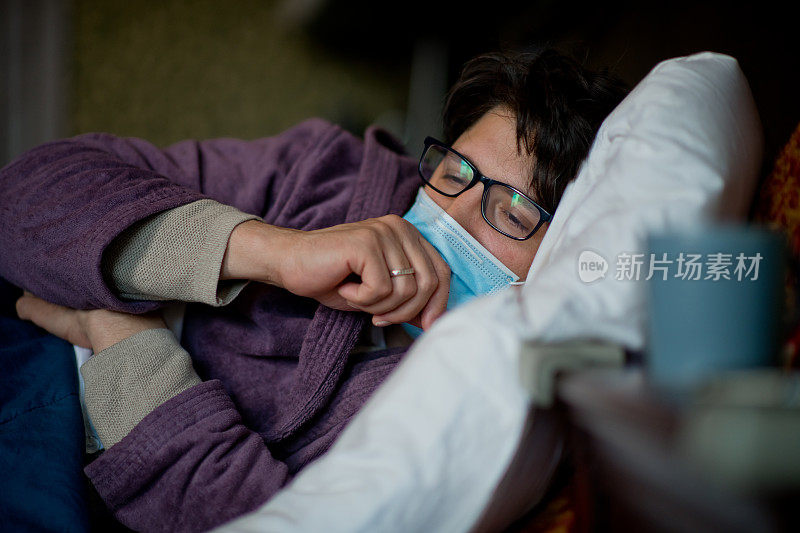 男子傍晚卧病在床，戴着防护口罩，因病毒病而精疲力竭