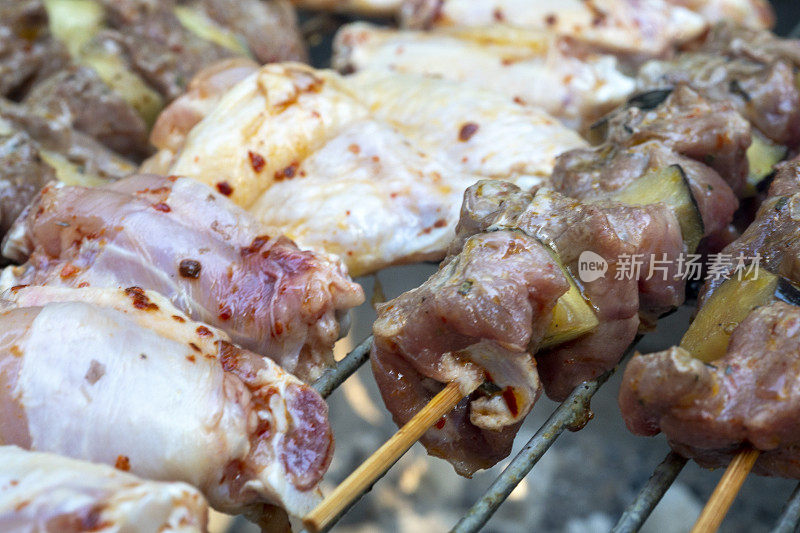 在花园烧烤烹饪猪肉，鸡肉，小牛肉和羊肉串在火盆上