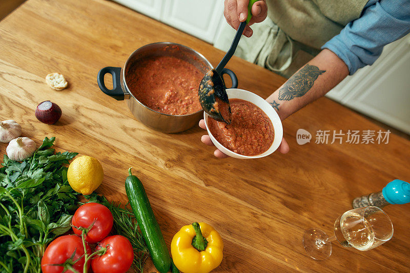 近距离的男人的手倒美味的汤从锅到碗。意大利厨师在厨房里准备传统菜肴。在家做饭，意大利菜