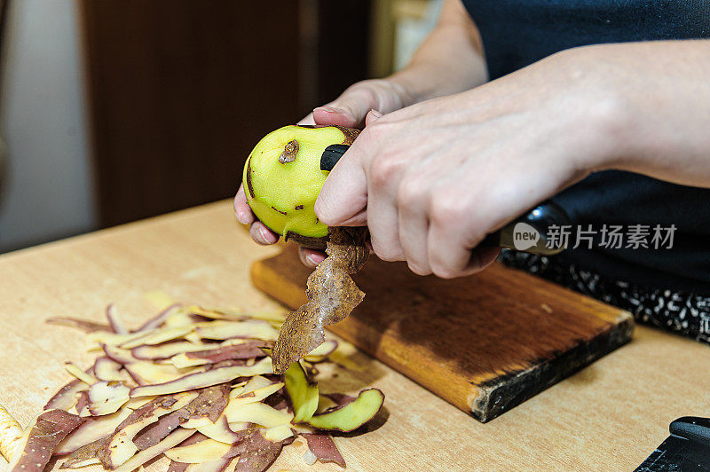 女性手的特写照片，这削土豆与厨房刀。