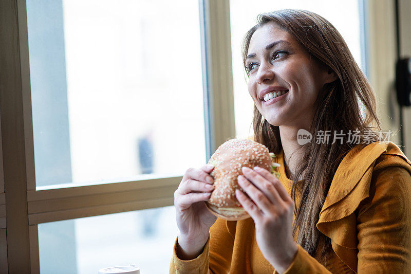 微笑的女士吃汉堡。