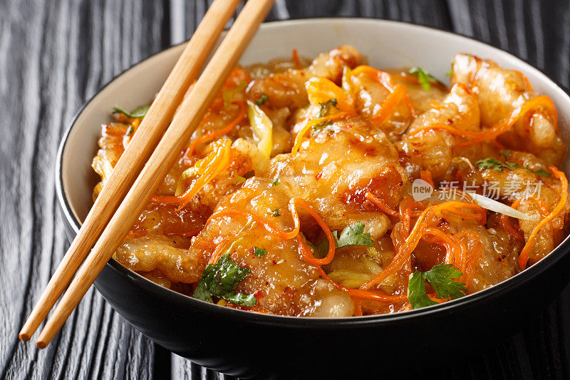 中国糖醋猪肉与胡萝卜，洋葱，大蒜和生姜在碗里特写。水平