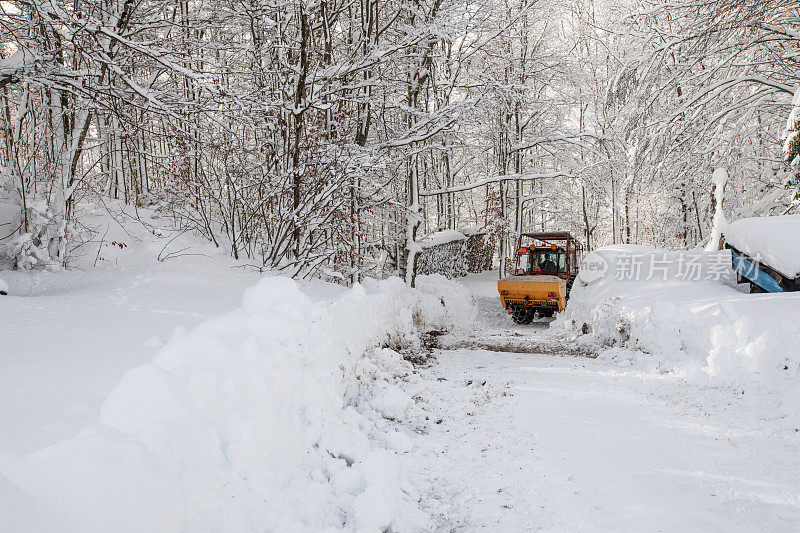 冬季林地土路上的扫雪机和撒盐机