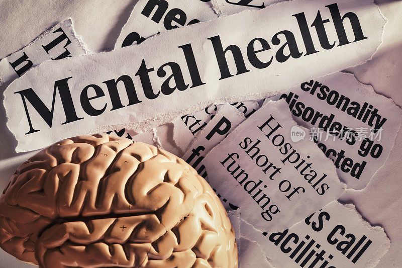 关于心理健康的报纸头条，旁边是一个人脑模型