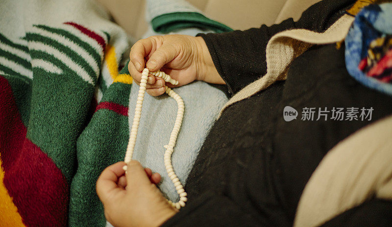 一位上了年纪的穆斯林妇女一边用念珠祈祷，一边用手的细节。